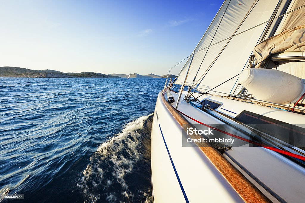 Navigation à voile dans le vent avec voilier au coucher du soleil - Photo de Bateau à voile libre de droits