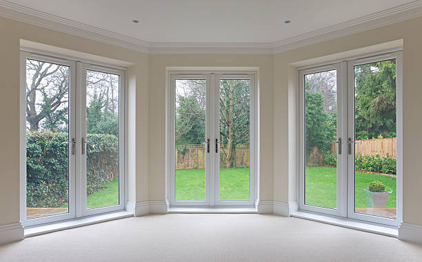 bay window patio doors ﻿a large bay window in an expensive new home comprising high quality white double-glazed door units all leading out to the garden. patio doors stock pictures, royalty-free photos & images