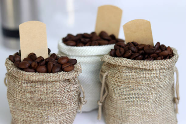 istock Coffee beans in burlap bags with blank labels on white background. 1660387054