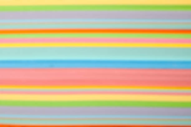 Side view of defocused multicolored paper stripes forming a colorful background.