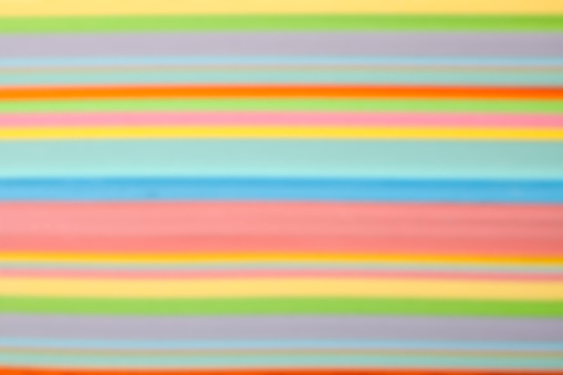 Side view of defocused multicolored paper stripes forming a colorful background.