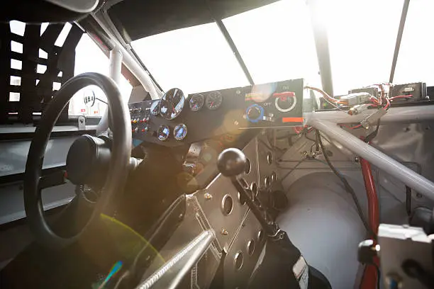 Interior of a stock car with glaring sunlight streaming through front windshield.