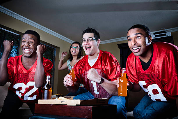 freunde beobachten fußballspiel auf fernseher - sitting 20s adult american football stock-fotos und bilder