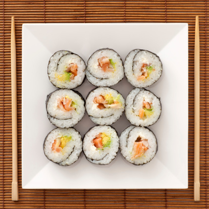 Sliced salmon sushi roll displayed on a white tray.