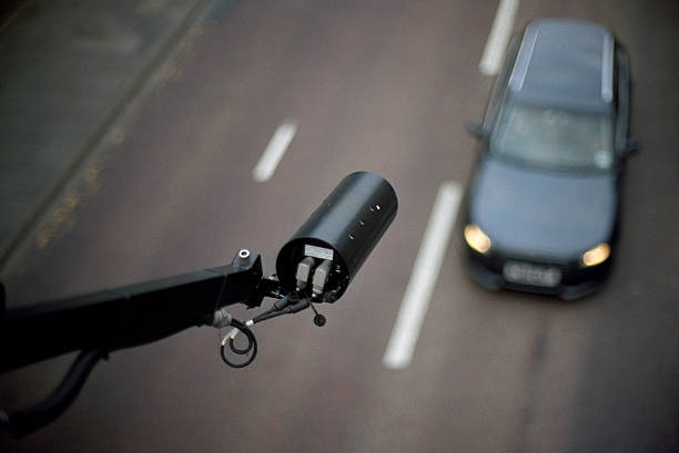 CCTV pointing on car - view from above, blurred background CCTV mounted over an English main road. Focus on the camera only. Wide aperture (f:1.2) to isolate the foreground. Some natural vignetting occurring. big brother orwellian concept photos stock pictures, royalty-free photos & images