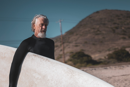 A mature man surfing the waves of Malibu, California USA