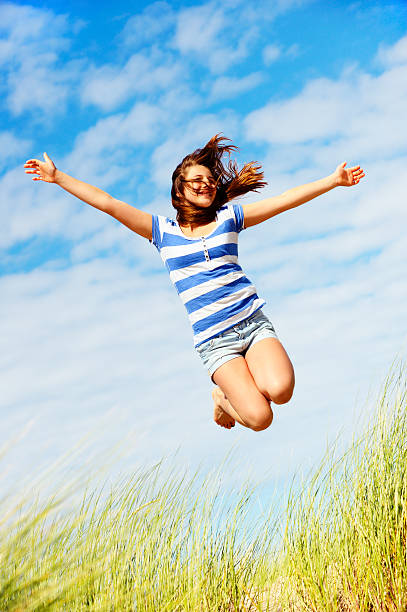 menina saltar sobre as dunas - arms outstretched teenage girls jumping flying imagens e fotografias de stock