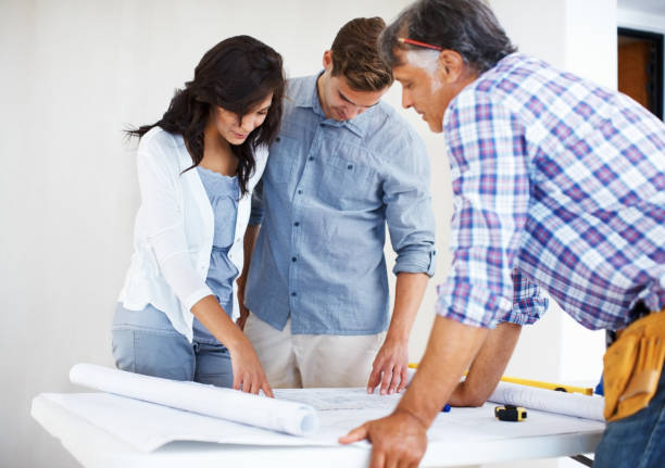 istock Young couple discussing house plan with architect 166052473