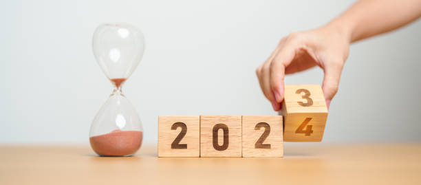 istock hand flipping block 2023 to 2024 text with hourglass on table. Resolution, time, plan, goal, motivation, reboot, countdown  and New Year holiday concepts 1660525394