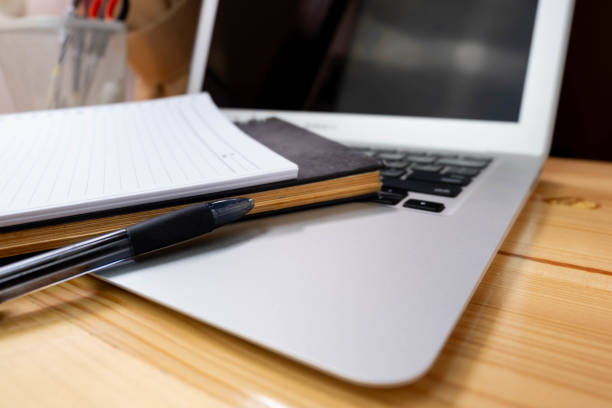 istock Image of workplace in office room without people with open laptop, pencil and notebook lying on wooden desk 1660557520