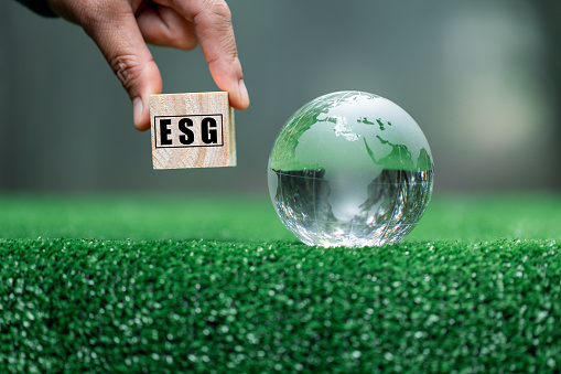Hand holding ESG word on a wooden cube on nature background. ESG Environmental, social, and corporate governance concept. Nature Сonservation, Ecology, Social Responsibility and Sustainability.