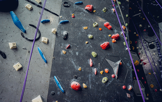 Artificial climbing wall with colorful grips and ropes.