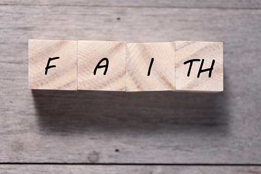 Faith symbol. Turned wooden cube with words Faith. Beautiful wooden table background. Business and Faith concept. Copy space