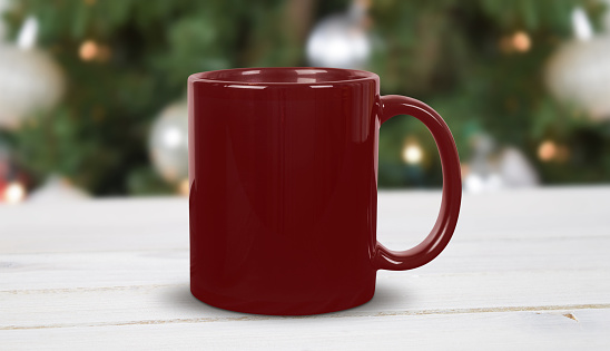 Closeup of red 11 oz. coffee cup resting on a modern white wood tabletop surrounded by glowing white Christmas lights.