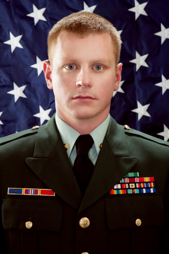 Decorated American Soldier with Class A Uniform Against USA Flag.