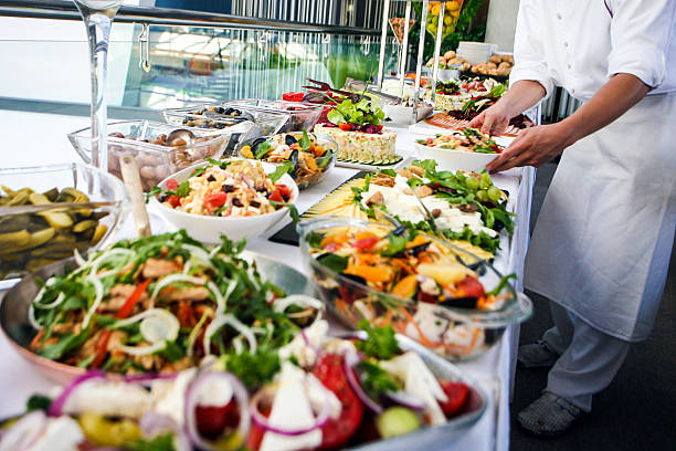 Waiter serving a buffet table Waiter serving a large buffet table full of delicious food. Unrecognizable Caucasian male, professional in white apron and uniform. people banque stock pictures, royalty-free photos & images
