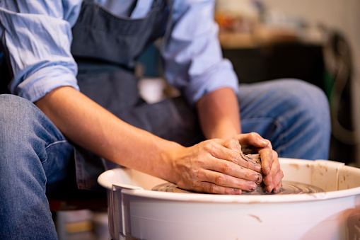 earthenware The art of sculpting clay with ceramics being molded by hand on a spinning machine. with the right posture to create a plate or vase professionally