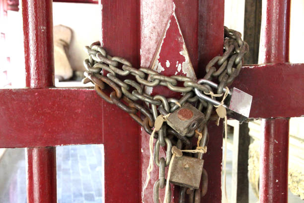 istock Three large iron chains and padlocks for thick, old, red wooden doors. 1660678633