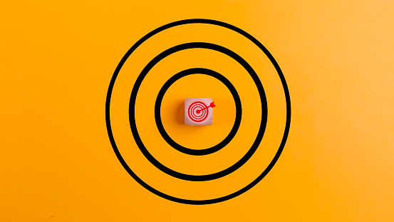 Concept of success. Target with a target icon on a wooden block on a yellow backgroundâthe concept of achieving or targeting business goals.