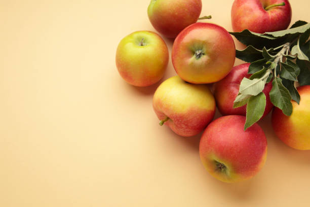 istock Ripe red apples with green leaves on beige background. 1660703359