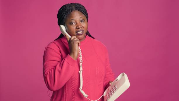 femme parlant par téléphone combiné - serious african ethnicity mid adult bright photos et images de collection