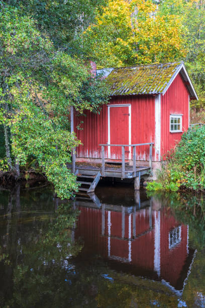istock Red small cottage by the water with autumn colors 1660727749
