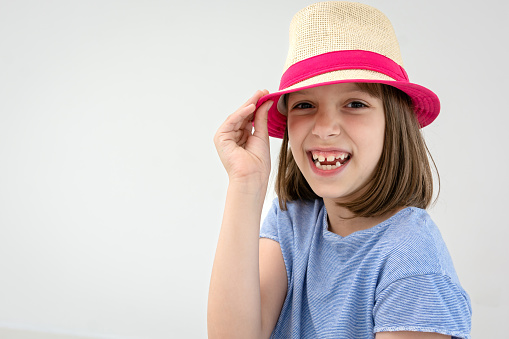 Portrait of a happy girl whit sun hat against white background looking at camera