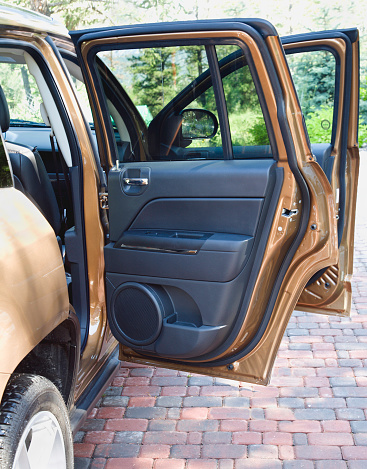New SUV.  Interior of passenger doors. Large speaker in door. Copper color. Parked on brick driveway.