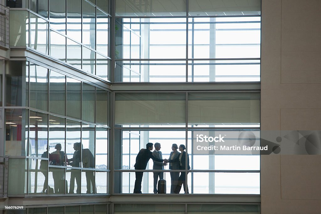 Las personas de negocios hablando en pasillo de oficina moderna - Foto de stock de Silueta libre de derechos