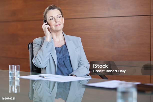 Sonriente Mujer De Negocios Hablando Por Teléfono Celular En La Sala De Conferencias Foto de stock y más banco de imágenes de 60-64 años