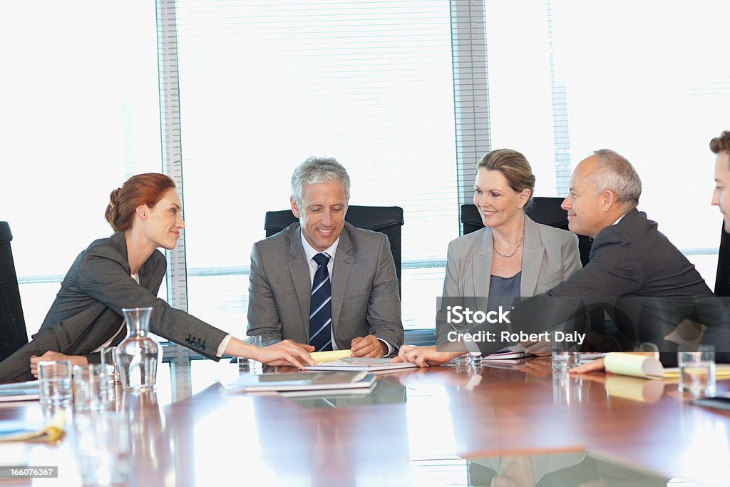 Sorridente uomini d'affari al tavolo riunione in una sala conferenze - Foto stock royalty-free di 30-34 anni