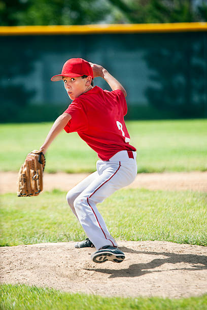 Youthful Male Baseball Pitcher Eyes Camera Winding Up on Moung A 12 year old boy concentrates on his target as he pitches from mound. baseball pitcher baseball player baseball diamond stock pictures, royalty-free photos & images
