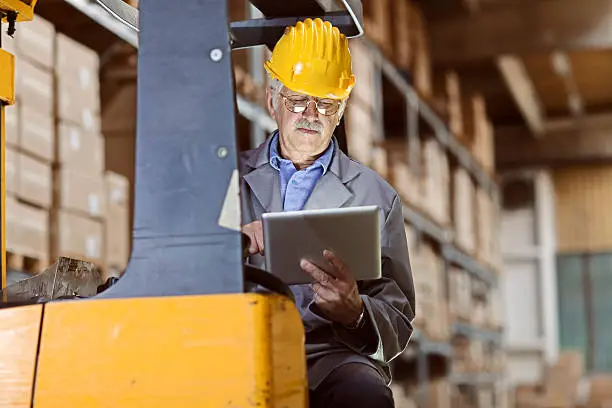 Photo of forklift operator at warehouse use digital tablet  for reviewing  inventory