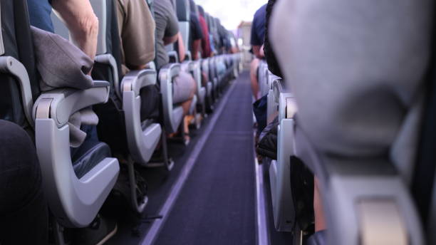 People sitting in the aisle of the plane People sitting in the aisle of the plane passenger cabin stock pictures, royalty-free photos & images