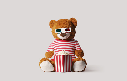 Cute teddy bear watching movies and eating popcorn