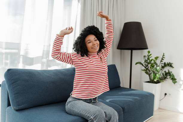 Portrait of smiling beautiful African American woman in casual clothes sitting on comfortable sofa