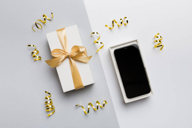istock Opened gift box with gold ribbon and smartphone on color background, top view. Blank open box packaging mockup , Template for your design - branding mockup 1660832542