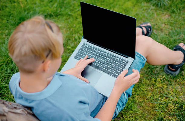 istock young boy on a grass in the park or garden using laptop 1660855109