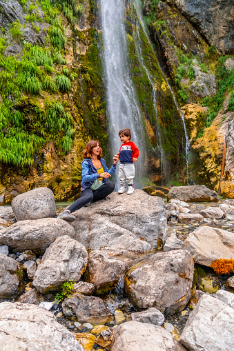 Mother with her son Grunas waterfall in Theth national park, Albania. Albanian alps