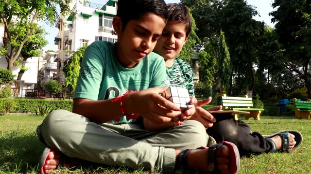 Two children playing with rubiks or rubix cube and using digital tablet