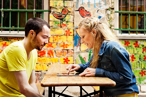 giovane coppia con computer tablet in café - east germany berlin germany graffiti wall foto e immagini stock