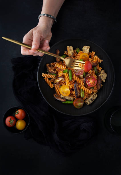 istock Fusilli pasta with mushrooms, asparagus and cherry tomatoes as closeup on a modern design plate and dark background 1660866925