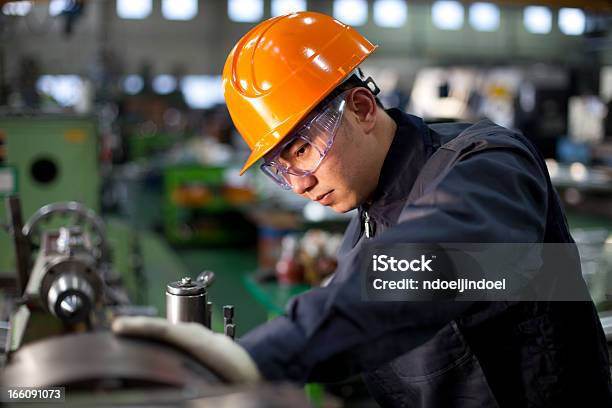 Technician In Uniform And Hard Hat Working On A Machinery Stock Photo - Download Image Now