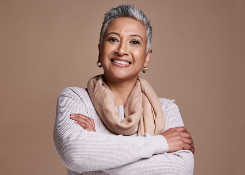 Face, fashion and style with a senior woman in studio on a brown background to model contemporary clothes. Portrait,  fashionable and stylish with a mature female posing to promote a clothing brand