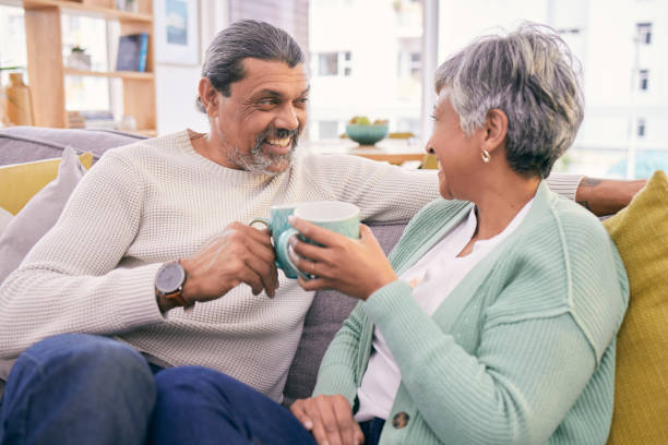 istock Coffee, talking and mature couple on sofa for bonding, healthy relationship and connection. Marriage, love and happy man and woman drinking tea on couch to relax in discussion, conversation and chat 1660915256