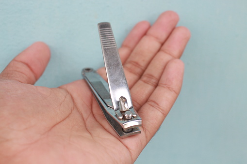 Close-up of man's hand holding nail clippers on blur background