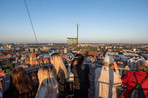 Gdansk, Poland - October 7, 2022 - People on viewpoint terrace of St Mary Basilica tower overlooking the Old Town at sunset.