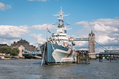 London, England - 29th July 2023: HMS Belfast, a 9 deck World War 2 navy warship, moored in front of Tower Bridge on the River Thames in London