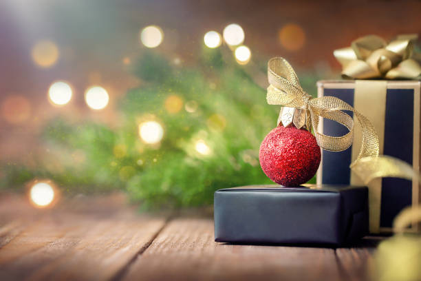 istock two black gift boxes decorated with a gold ribbon and a bow. Next to the Christmas tree and garlands. place for text 1661013375