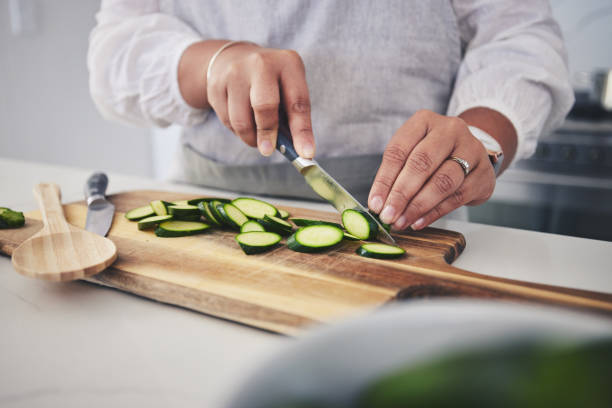 istock Cut, cucumber and hands cooking vegetable in a kitchen on a board or table in a home for hygiene as a chef. Salad, food and person prepare produce for a supper, lunch or dinner for diet meal 1661015579
